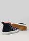 Introducing the CSW 2: A pair of black high-top sneakers meticulously crafted from premium canvas, featuring white soles, red accents, and visible stitching. One sneaker stands upright while the other rests on its side, revealing the honeycomb-patterned sole. Handcrafted in Portugal for those who value quality and style.