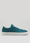 The V8 Petrol Blue sneaker is a low-top design in teal, featuring white laces and a white sole. It is handcrafted in Portugal using premium Italian leathers and is set against a light gray background.