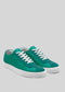 A pair of V3 Emerald Green low-top sneakers, featuring white soles and laces, handcrafted in Portugal from premium Italian leathers, are set against a gray background.