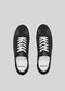 Top view of the V1 Black, a pair of exquisitely handcrafted black low-top sneakers with white laces from Portugal, placed on a gray background.