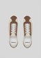 Top view of the V11 Beige W/ Caramel sneakers, handcrafted in Portugal with premium Italian leathers, featuring brown and beige tones with white laces on a light gray background.