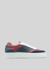 La N0016 di Daniel presenta una vista laterale di una sneaker low-top con suola bianca e tomaia in pelle con pannelli di colore rosso scuro, blu navy e grigio. Realizzata a mano in Portogallo con pellami italiani di prima qualità, questa sneaker vanta lacci bianchi e una suola con plateau leggermente rialzata.