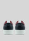 The image displays the rear perspective of N0016 by Daniel, a pair of handcrafted black and red sneakers with white soles from Portugal, set against a gray background.