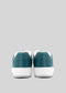 Rear view of a pair of teal sneakers with white soles, handcrafted in Portugal using premium Italian leathers, against a gray background. These are M0005 by Sandro.