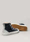 A pair of navy blue and gray high-top sneakers with white soles are displayed. One shoe is upright, and the other is lying on its side to show the brown rubber sole pattern. Handcrafted in Portugal, these TH0017 by Khadija feature premium canvas and suede for an ethically made, stylish choice.