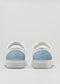 A pair of V38 White Leather W/Artic with light blue heel accents, handcrafted in Portugal, viewed from the back.