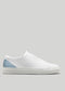 A V38 White Leather W/Artic with a blue heel accent and a white sole, viewed from the side against a plain grey background, showcases its elegance. Handcrafted in Portugal using premium Italian leathers, these customizable sneakers offer both luxury and personal flair.